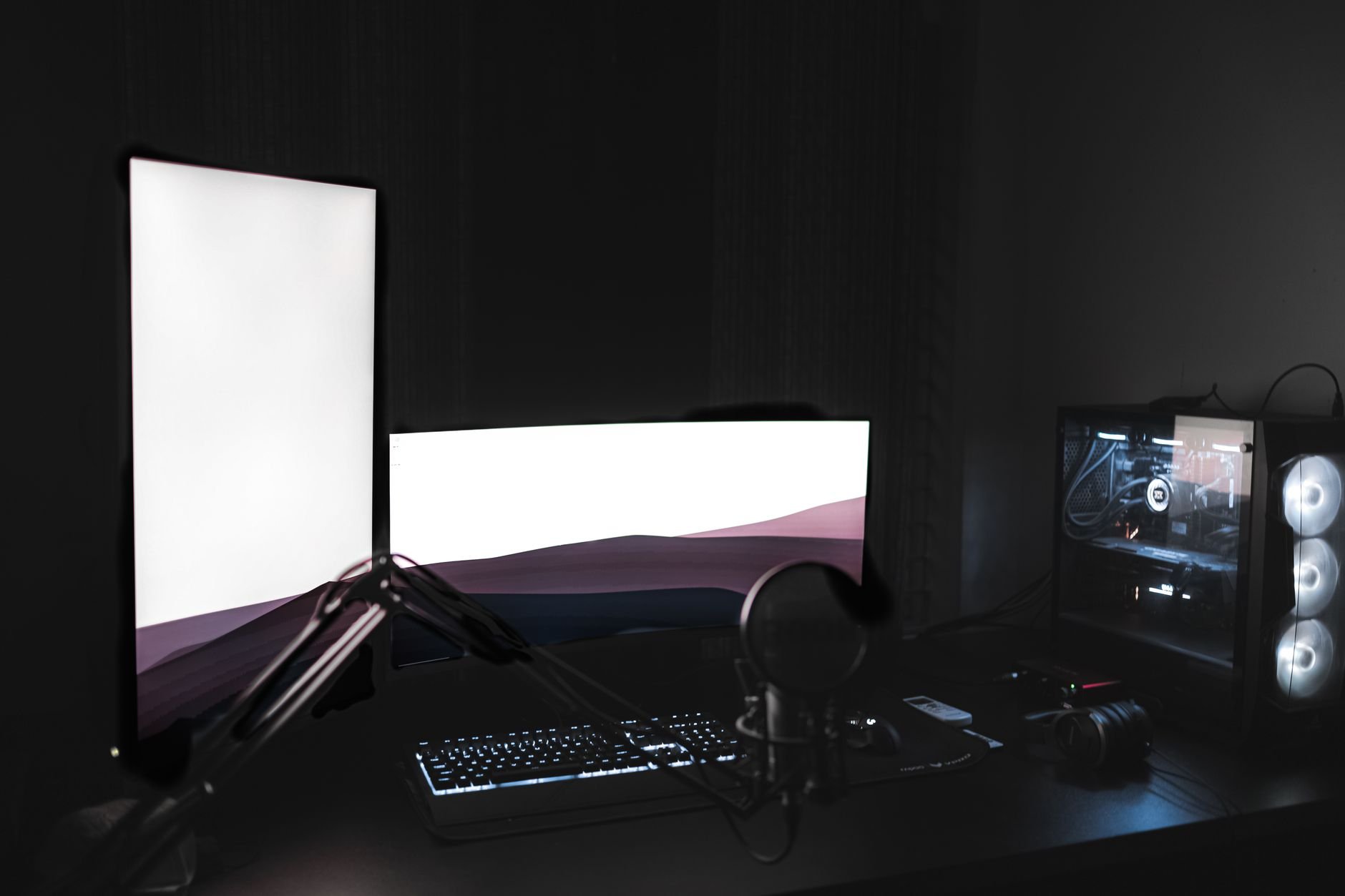 Gaming setup with glowing monitors in a dark room